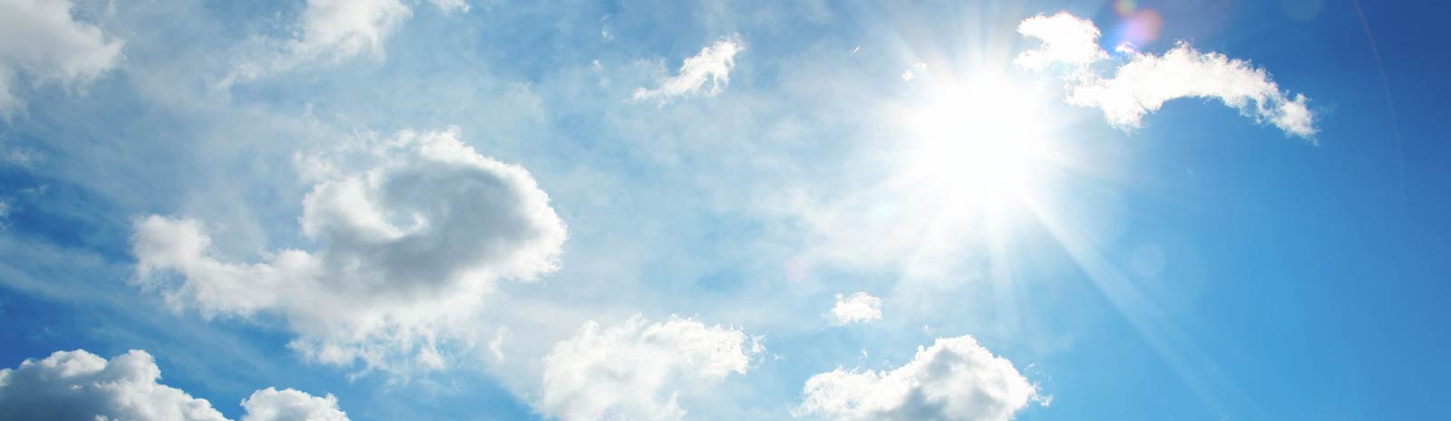 Sky filled with fluffy clouds and sun shining through.