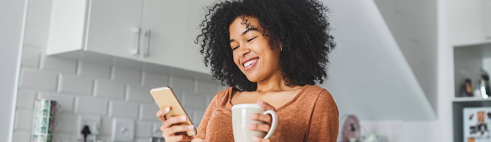 Young woman drinking tea and using her phone.